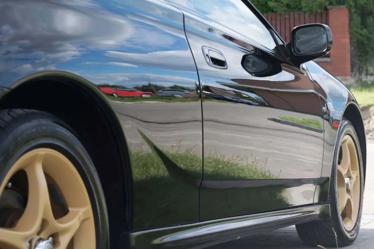 clean black car paint with glossy reflection after proper washing and drying using microfiber towel