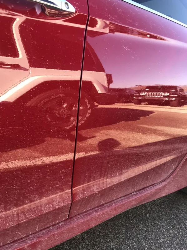 dull red car paint with traffic film and dirt after washing