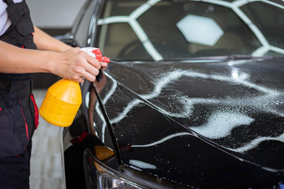 spraying alkaline pre wash foam on car surface before contact wash detailing